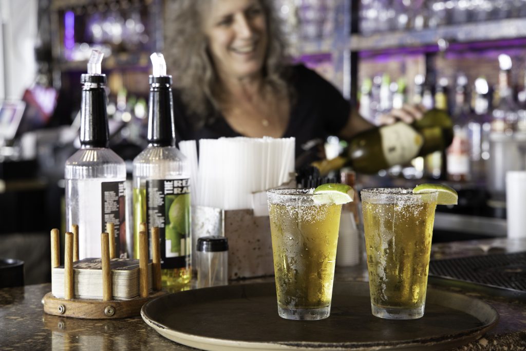 A woman is sitting at the bar with two drinks.