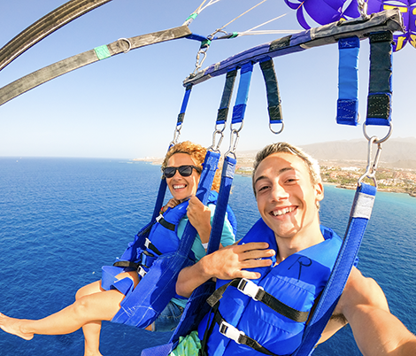 Two people on a parachute over the ocean.